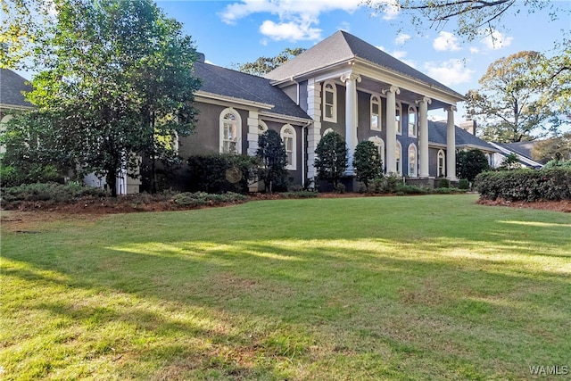 neoclassical home featuring a front lawn