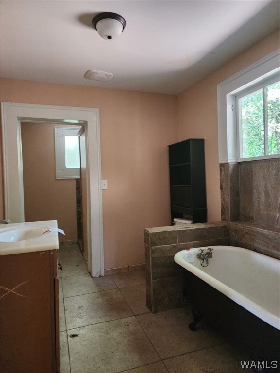 bathroom featuring tile patterned flooring, vanity, and a tub to relax in