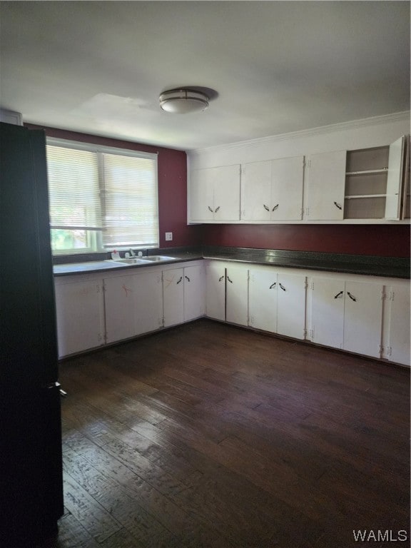 kitchen featuring black fridge, dark hardwood / wood-style flooring, white cabinets, and sink