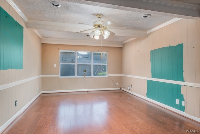 empty room featuring beamed ceiling, wood-type flooring, ornamental molding, and a textured ceiling