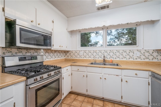 kitchen featuring white cabinetry, sink, crown molding, a textured ceiling, and appliances with stainless steel finishes