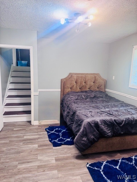 bedroom featuring a textured ceiling, wood finished floors, and baseboards