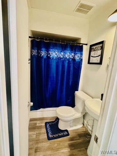 bathroom featuring wood finished floors, toilet, a shower with curtain, and ornamental molding