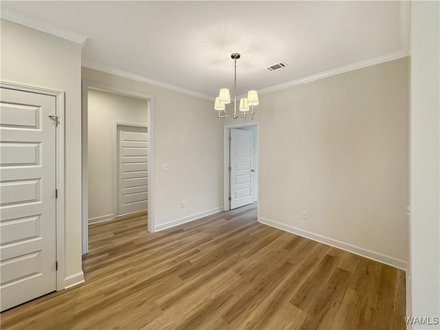 unfurnished room with wood-type flooring, crown molding, and an inviting chandelier