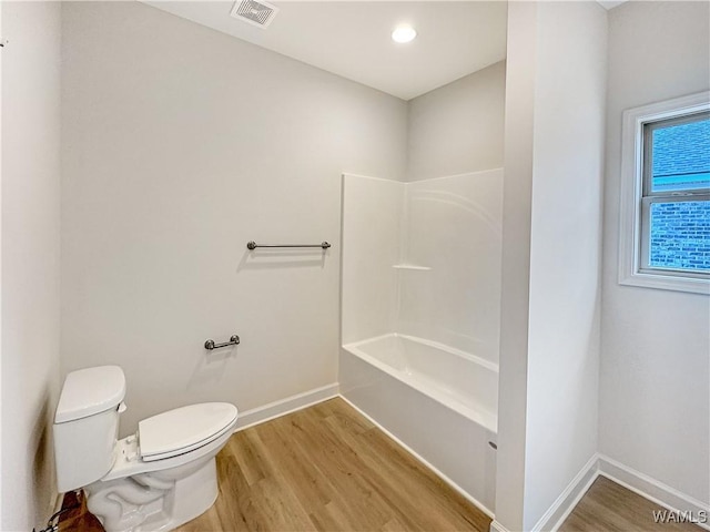 bathroom featuring wood-type flooring, bathtub / shower combination, and toilet