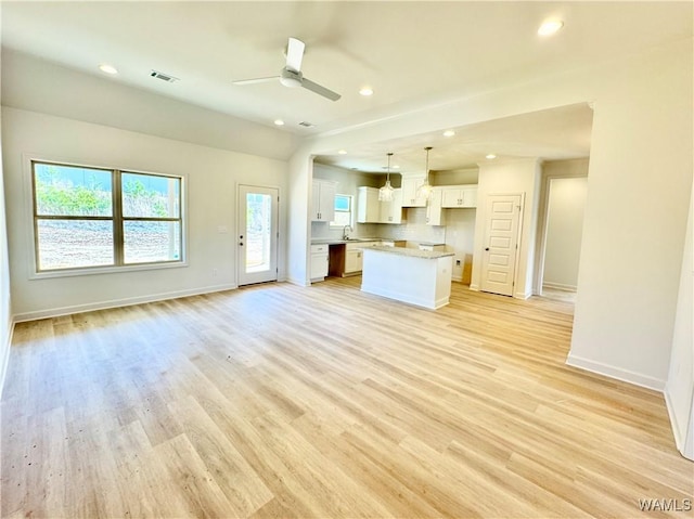 unfurnished living room featuring ceiling fan, sink, and light wood-type flooring