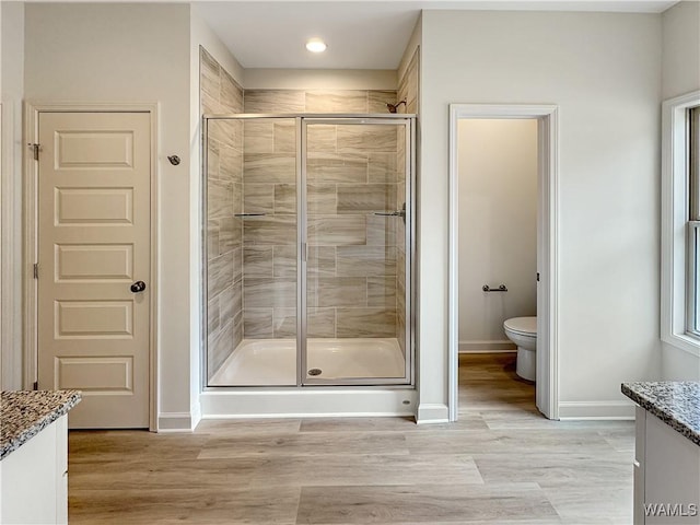 bathroom with vanity, toilet, an enclosed shower, and wood-type flooring