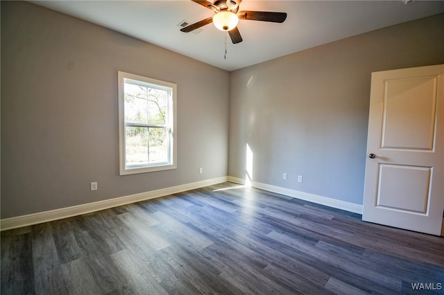 spare room with dark wood-type flooring, ceiling fan, and baseboards
