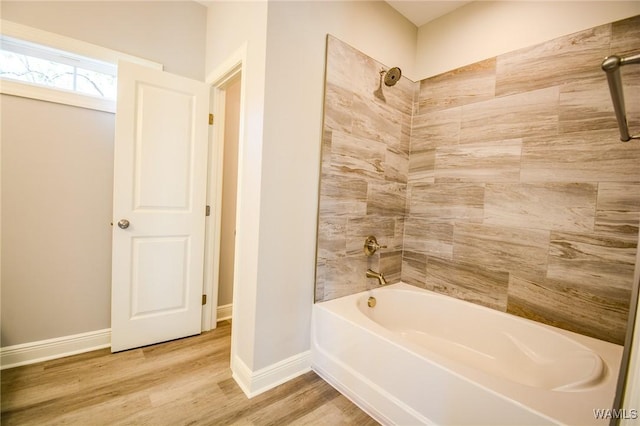 bathroom featuring wood-type flooring and tiled shower / bath