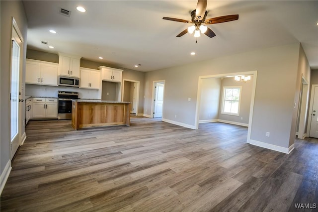 kitchen with appliances with stainless steel finishes, white cabinetry, a center island, and wood-type flooring