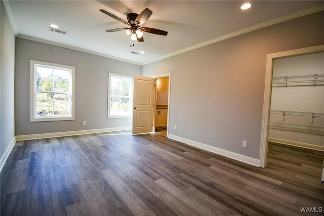 unfurnished bedroom with ceiling fan, ornamental molding, a closet, a walk in closet, and dark hardwood / wood-style flooring