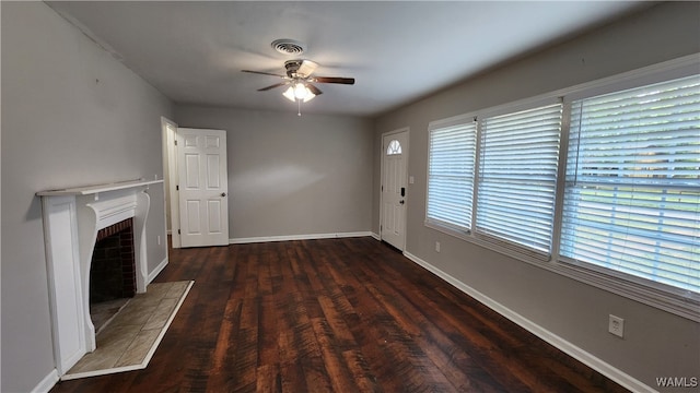 unfurnished living room with a tile fireplace, plenty of natural light, dark wood-type flooring, and ceiling fan