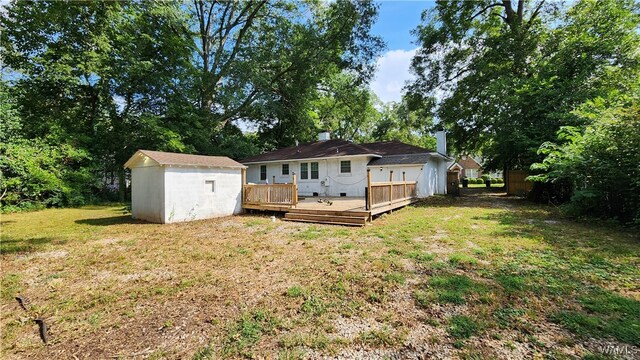 rear view of property featuring a wooden deck, a yard, and a shed