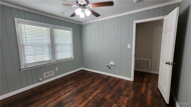 spare room featuring dark hardwood / wood-style flooring, ceiling fan, crown molding, and wood walls