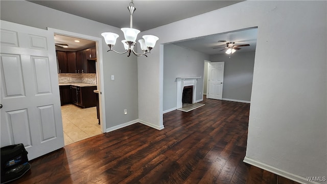 unfurnished dining area featuring ceiling fan with notable chandelier and hardwood / wood-style flooring