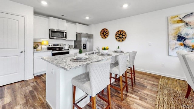 kitchen featuring dark hardwood / wood-style floors, white cabinetry, a kitchen island with sink, and appliances with stainless steel finishes