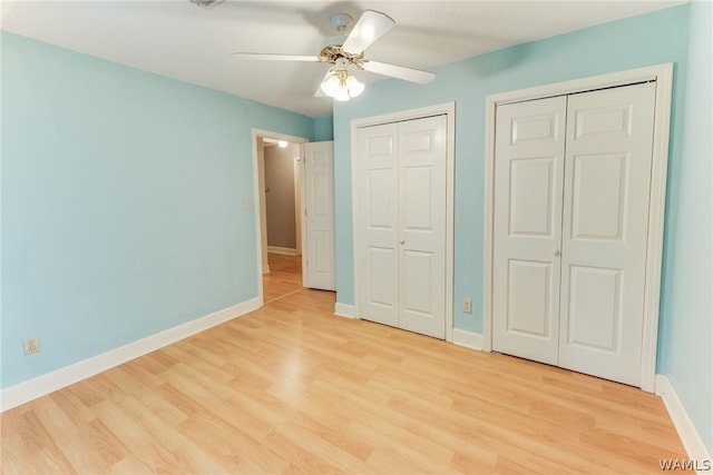 unfurnished bedroom featuring ceiling fan, two closets, and light hardwood / wood-style flooring