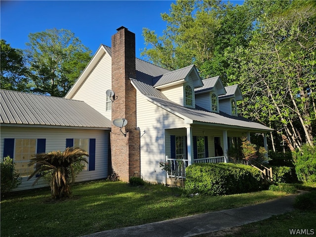 view of side of home featuring covered porch and a yard