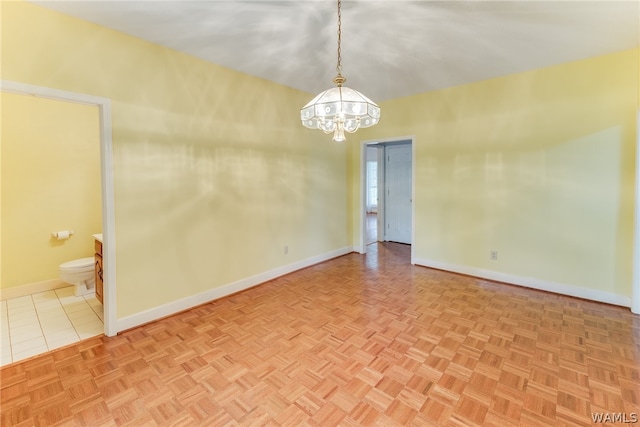 spare room featuring light parquet floors and an inviting chandelier