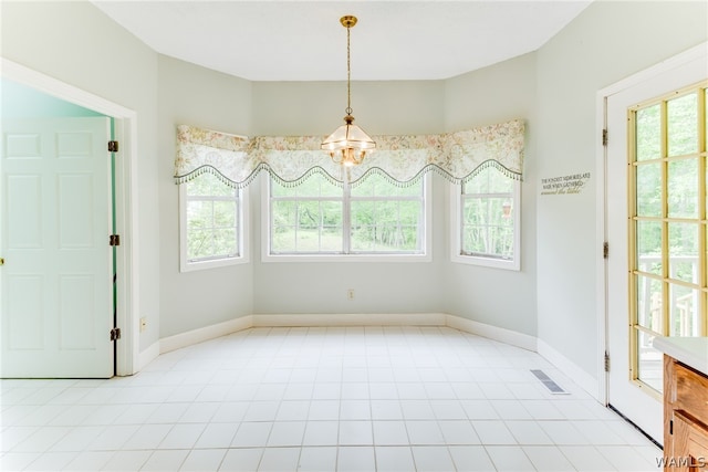 unfurnished dining area with a chandelier, light tile patterned floors, and plenty of natural light