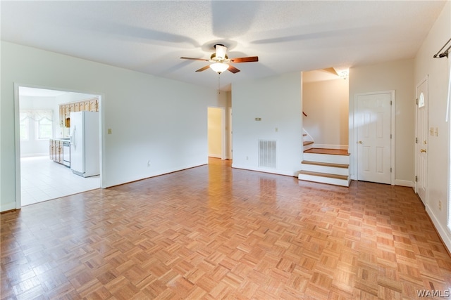 unfurnished room featuring a textured ceiling, light parquet flooring, and ceiling fan