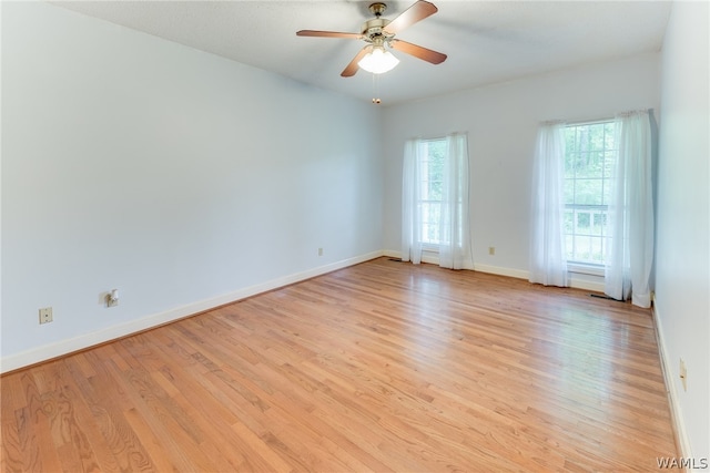 spare room with light hardwood / wood-style floors, a wealth of natural light, and ceiling fan