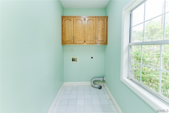 clothes washing area featuring electric dryer hookup, hookup for a washing machine, light tile patterned flooring, and cabinets