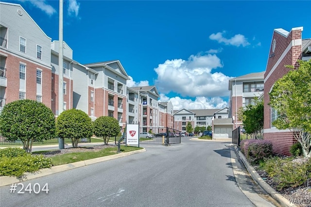 view of road with a gate, a residential view, a gated entry, and curbs