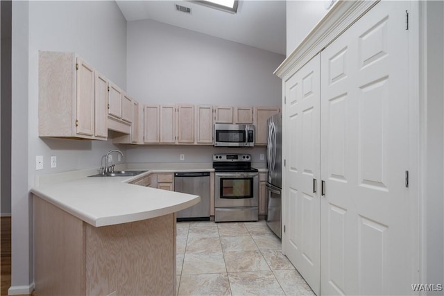 kitchen featuring light brown cabinetry, sink, high vaulted ceiling, appliances with stainless steel finishes, and kitchen peninsula