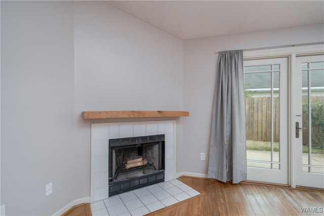 interior details with wood-type flooring and a tile fireplace