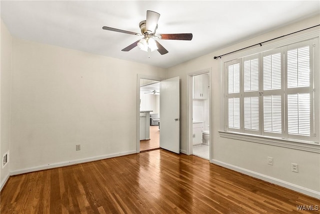 unfurnished bedroom with ensuite bathroom, visible vents, baseboards, and wood finished floors