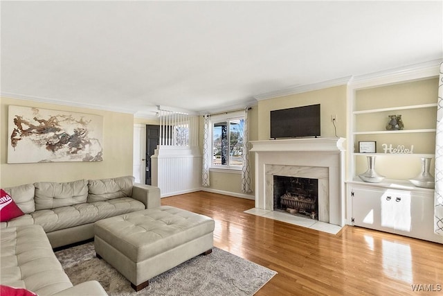 living area with crown molding, a premium fireplace, and wood finished floors