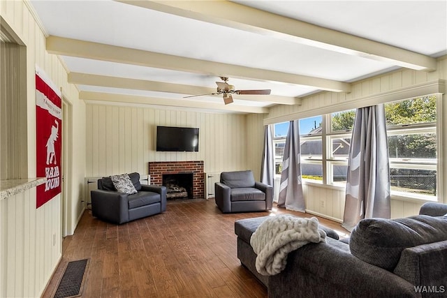 living area with visible vents, ceiling fan, dark wood-style flooring, a fireplace, and beam ceiling