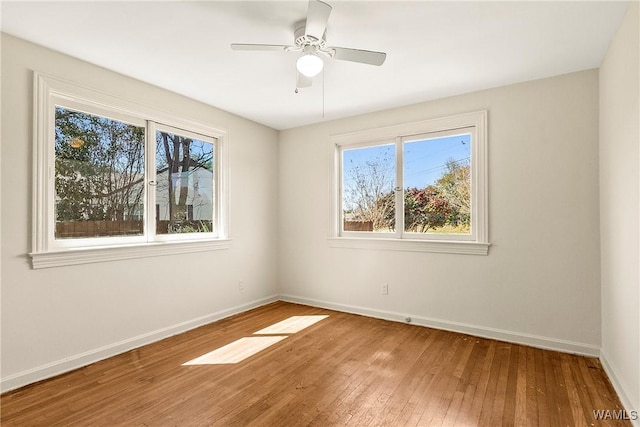 unfurnished room with a ceiling fan, baseboards, and hardwood / wood-style flooring