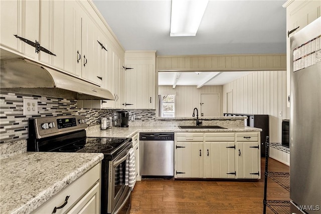 kitchen featuring decorative backsplash, dark wood-style floors, appliances with stainless steel finishes, under cabinet range hood, and a sink