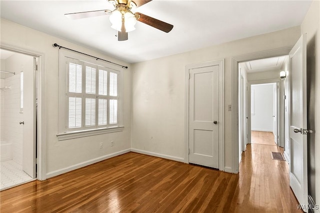 empty room with ceiling fan, wood finished floors, and baseboards