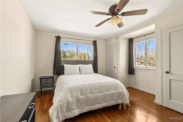 bedroom with a ceiling fan, baseboards, and wood finished floors