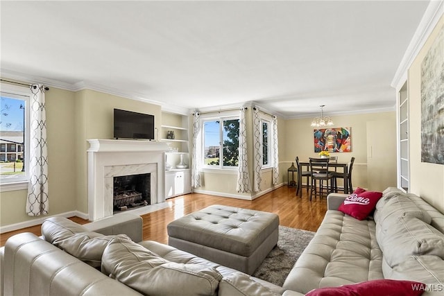 living area featuring crown molding, a premium fireplace, wood finished floors, and a healthy amount of sunlight