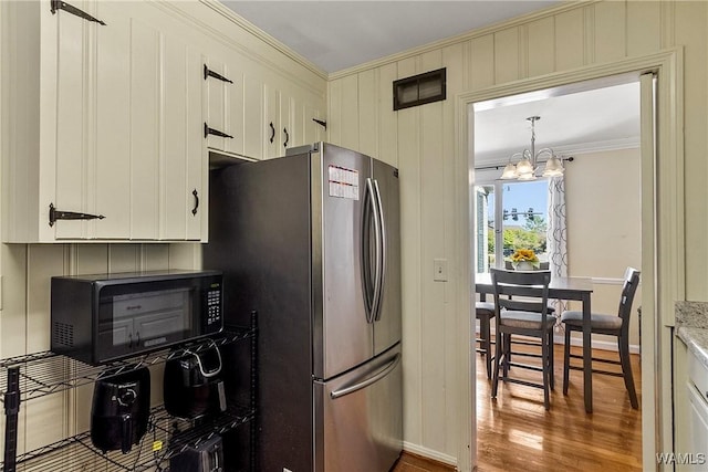 kitchen featuring a chandelier, wood finished floors, freestanding refrigerator, crown molding, and black microwave