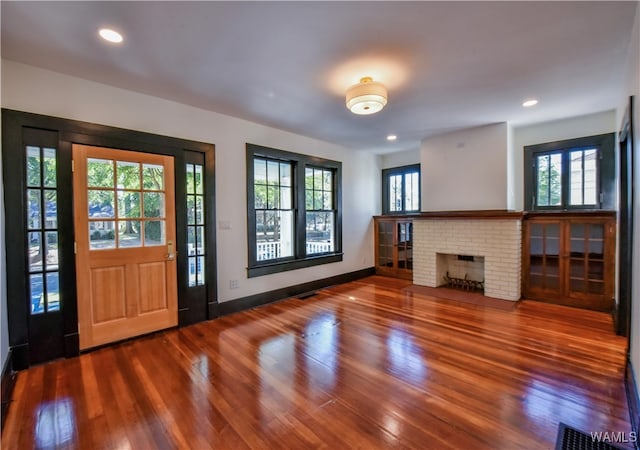 foyer featuring hardwood / wood-style floors, a brick fireplace, and plenty of natural light