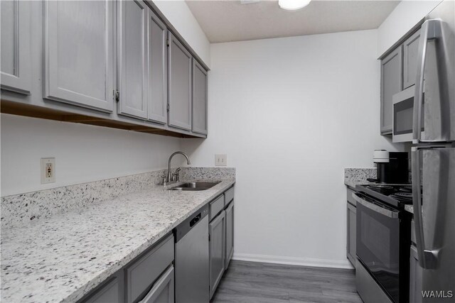 kitchen featuring appliances with stainless steel finishes, a sink, and gray cabinetry