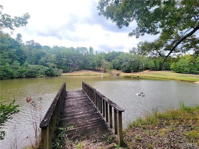 view of dock with a water view and a forest view