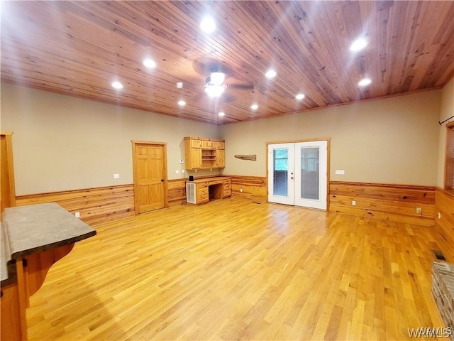 living area featuring french doors, a wainscoted wall, light wood finished floors, visible vents, and wood ceiling