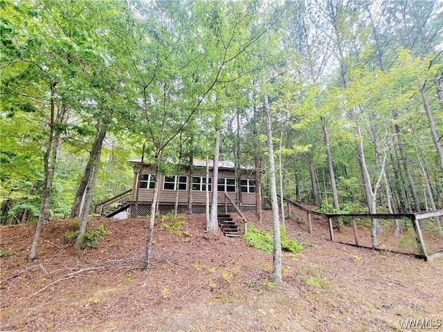 rear view of house with stairs and a forest view