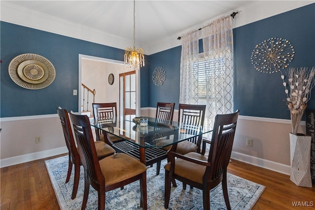 dining area with crown molding, dark wood-type flooring, and an inviting chandelier