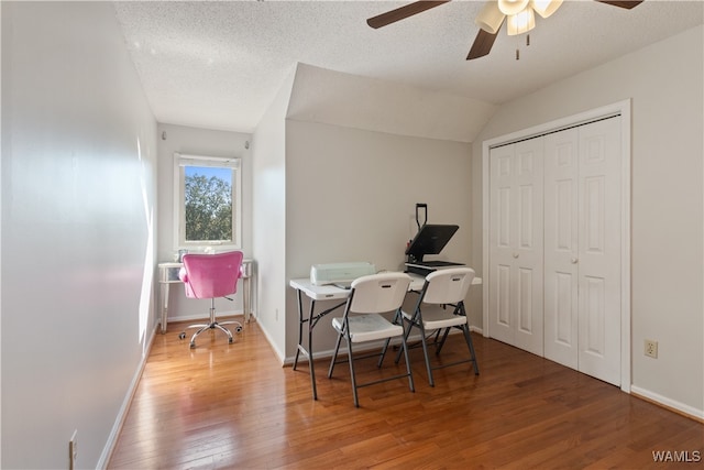 office area with a textured ceiling, ceiling fan, wood-type flooring, and vaulted ceiling