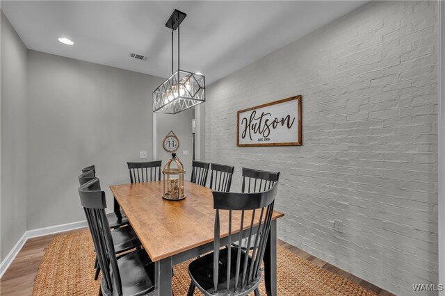 13930 Sullivan Blvd, Northport, AL 35475 - dining space with visible vents, wood finished floors, a chandelier, and brick wall
