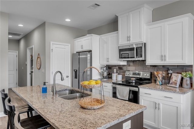 13930 Sullivan Blvd, Northport, AL 35475 - kitchen with visible vents, a sink, appliances with stainless steel finishes, a kitchen island with sink, and white cabinetry