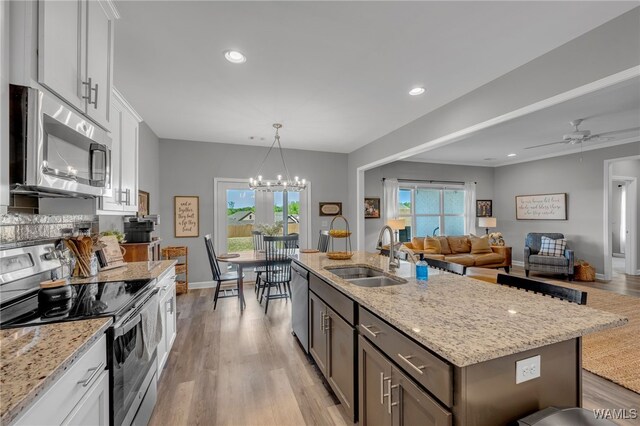 13930 Sullivan Blvd, Northport, AL 35475 - kitchen with light wood-type flooring, white cabinetry, light stone countertops, stainless steel appliances, and a sink