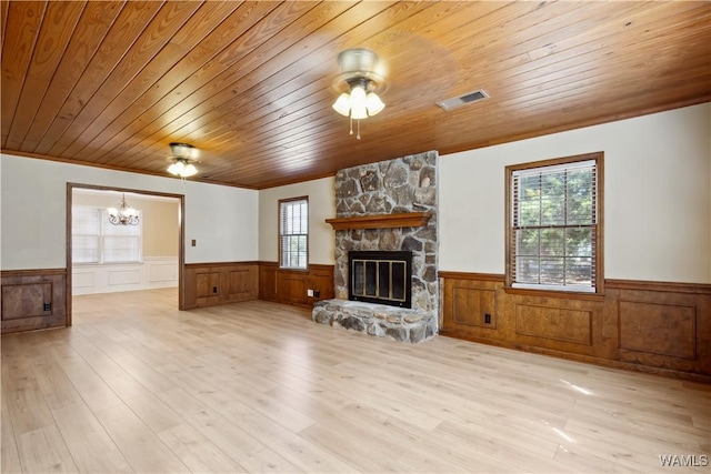 living area with wooden ceiling, a wainscoted wall, ceiling fan with notable chandelier, a fireplace, and visible vents